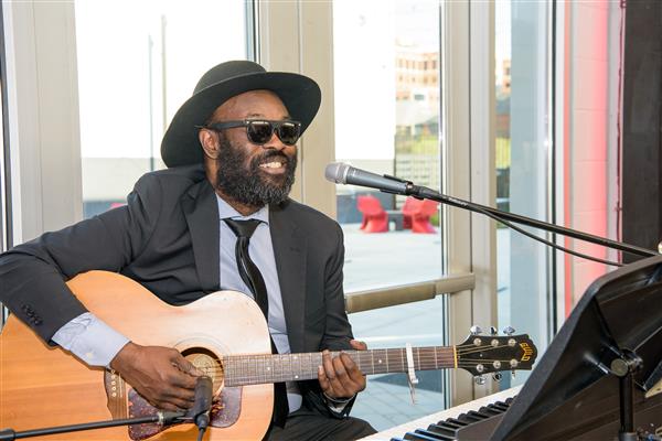 Dave Crenshaw plays his guitar and sings into a microphone.